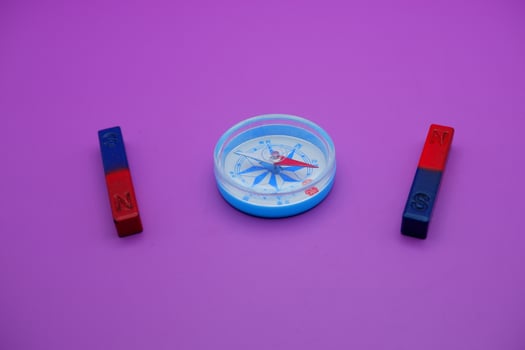 magnet and compass isolated on purple background photo
