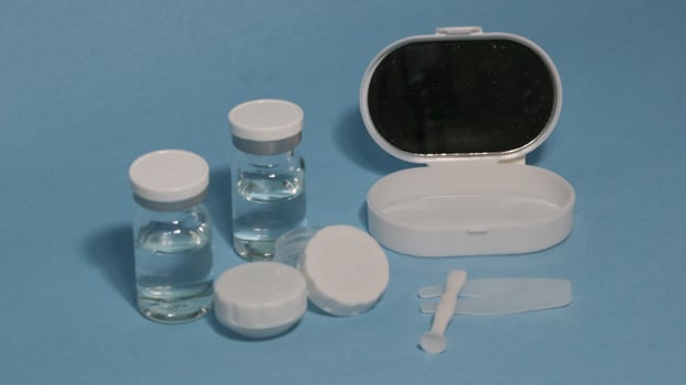 Container with tweezers, holder and contact lenses on a blue background photo