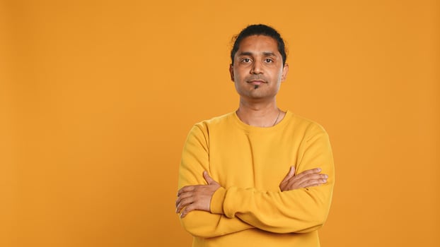 Portrait of cheerful friendly indian man smiling, looking pleased, isolated over yellow studio background. Happy expressive asian person grinning, feeling satisfied, camera A photo