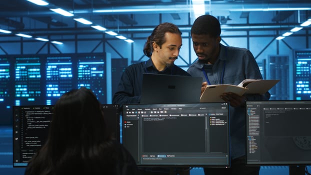 Inspector overseeing server room, reading paperwork and evaluating work done by multiracial team. Supervisor doing inspection in data center, examining hardware performance and workers output photo