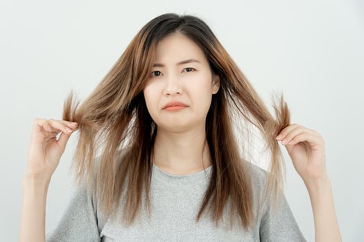 Asian woman very sad and upset looking at damaged hair, hair loss, hair thinning problem, vitamin deficiency, baldness, postpartum, biotin, zinc, menstrual or endocrine disorders, hormonal imbalance photo