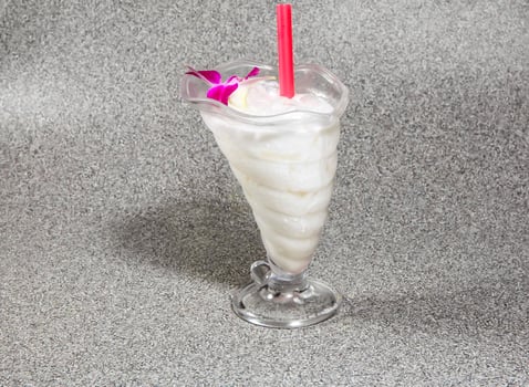 iced coconut milk with straw served in glass isolated on grey background side view of hong kong dessert drink photo