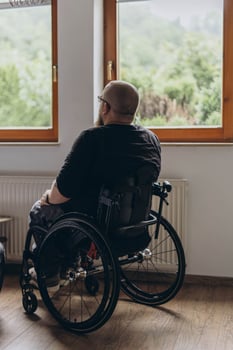 A young man sitting in a chair looking out the window photo