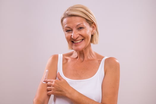 Portrait of beautiful mature woman applying moisturizer on her body photo