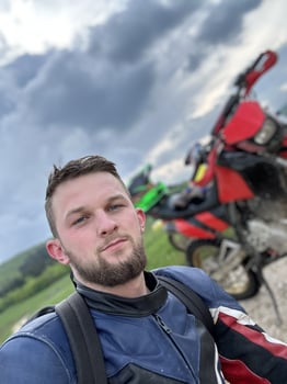 A professional motorcyclist resting on a forest road after an adventurous ride and taking a selfie for social networks photo