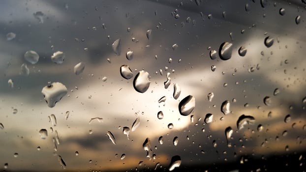 Rainwater drops cover on glass with cloud background photo