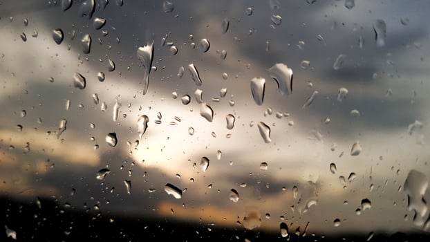 Rainwater drops cover on glass with cloud background photo