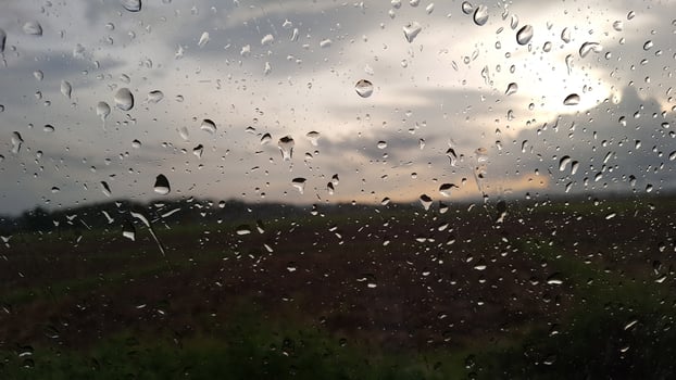Rainwater drops cover on glass with cloud background photo