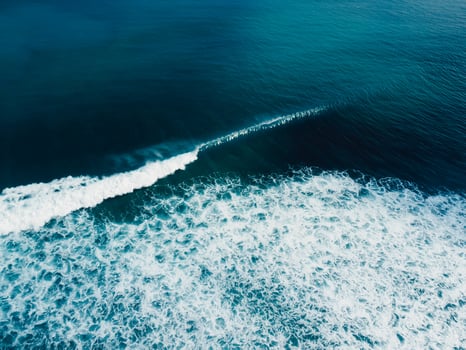 Breaking surfing wave in blue ocean. Drone view of swell photo