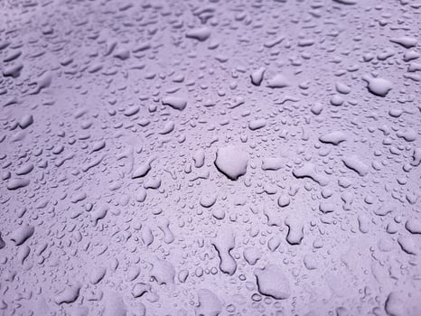 Large raindrops on the lilac hood of the car. photo