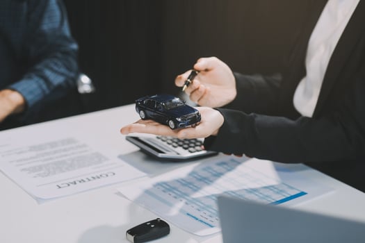 Car sales representative gives keys to new car owner, concept for car rental Focus on the key. Pick up the key. Close-up of the key transfer from the new machine to the buyer. photo