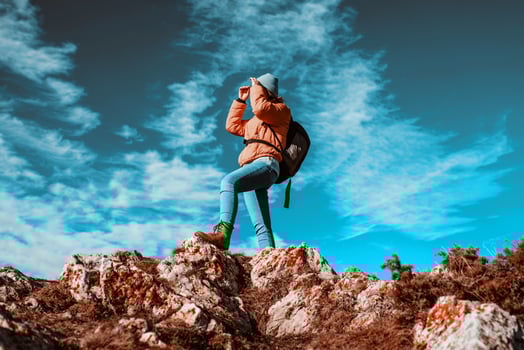 Cheering woman backpacker enjoy the view on sunrise mountain top cliff edge photo