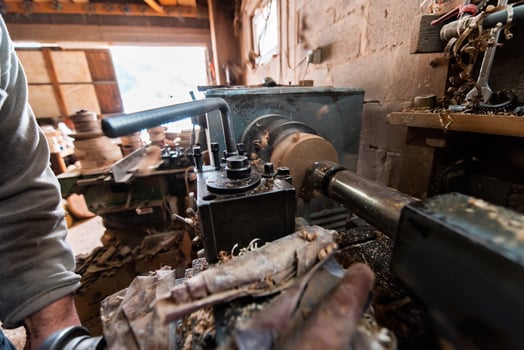 A senior man procesing wood on a lathe and making wooden dishes in the workshop photo