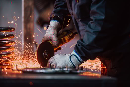 Locksmith in special clothes and goggles works in production. Metal processing with angle grinder. Sparks in metalworking. photo