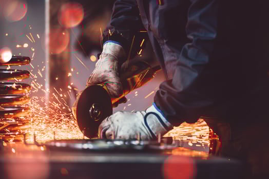 Locksmith in special clothes and goggles works in production. Metal processing with angle grinder. Sparks in metalworking. photo