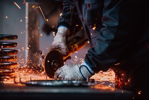 Locksmith in special clothes and goggles works in production. Metal processing with angle grinder. Sparks in metalworking. photo