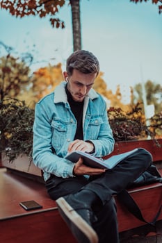 A student sitting in a park in front of the university and reading a book photo
