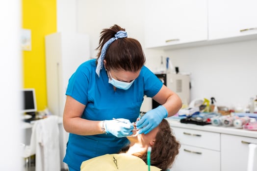 Dentist appointment at a dental clinic, placing braces locks on the teeth and pulling the archwire to fix it photo