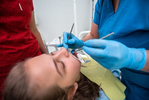 Dentist appointment at a dental clinic, placing braces locks on the teeth and pulling the archwire to fix it photo