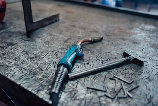 A hammer and a modern welding machine on a steel industrial table photo