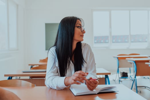 A black-haired female student wearing glasses is attentively engaged in a modern classroom, embracing education and learning with focus and curiosity photo