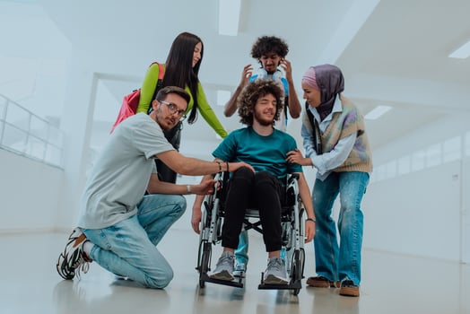 In a modern university, a diverse group of students, including an African American student and a hijab-wearing woman, walk together in the hallway, accompanied by their wheelchair-bound colleague photo
