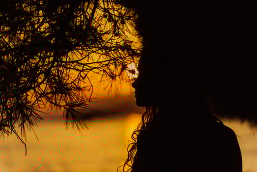 Silhouette of a girl enjoying a playful moment in the sea during sunset, her hair blowing in the wind, capturing the essence of carefree beach fun photo