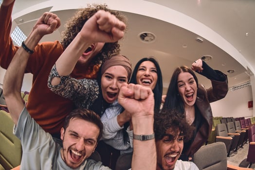 A diverse group of young people exuberantly celebrates and cheers while watching a soccer match, radiating excitement, unity, and sportsmanship photo