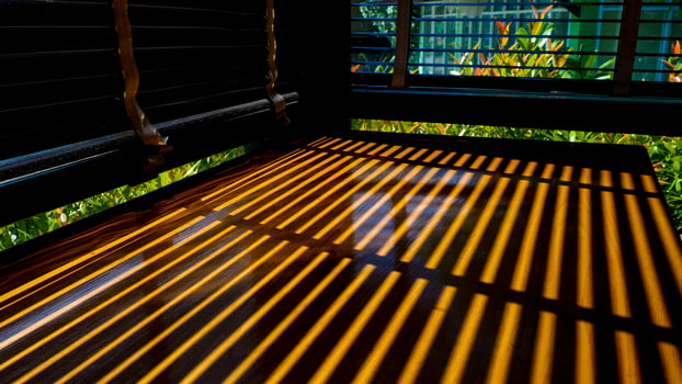 Sunlight Casting Striped Shadows Through Window Blinds onto Wooden Table in a Cozy Room photo