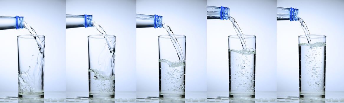Sequence of Water Being Poured into a Glass from a Bottle in Five Stages on a White Background photo