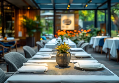 Restaurant Table Setting With Plant Decor. Close-up of a restaurant table with white linens, silverware, and a potted plant centerpiece. photo