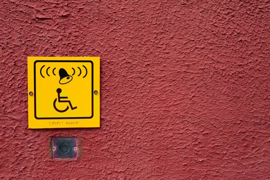 Wheelchair icon with bell and braille text on red wall next to button to call help for disabled person photo