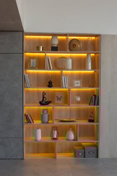 A shelving with figurines, vases and frames, with warm lighting, stands in a niche of the wall photo