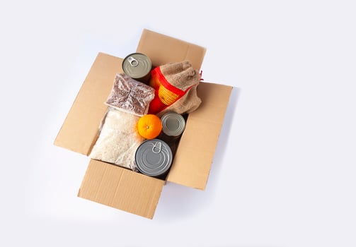 Canned food, fresh apple fruits, buckwheat and rice packs in a cardboard box. Food donation, delivery theme. photo