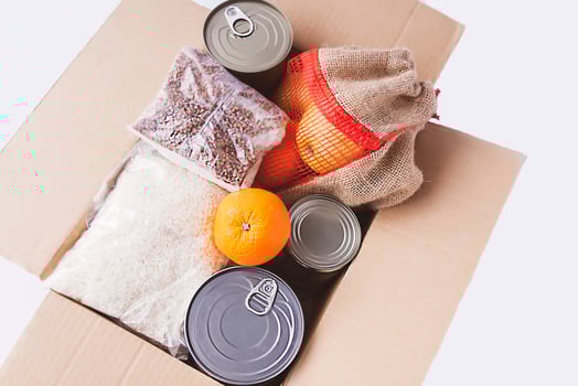 Canned food, fresh apple fruits, buckwheat and rice packs in a cardboard box. Food donation, delivery theme. photo