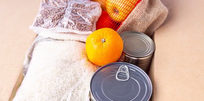Canned food, fresh apple fruits, buckwheat and rice packs in a cardboard box. Food donation, delivery theme. photo