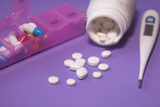 colorful pills spilling from container on color background photo