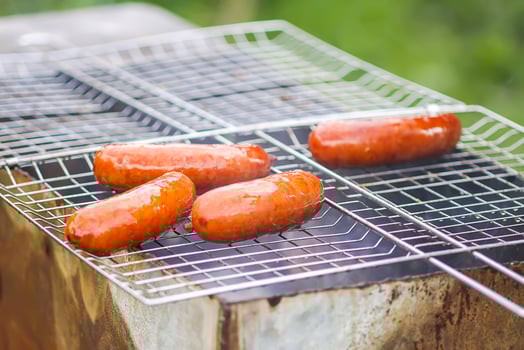 Tasty grilled sausages. Frying on brazier outdoors in the countryside at summer. photo