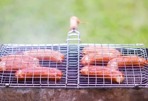 Tasty grilled sausages. Frying on brazier outdoors in the countryside at summer. photo
