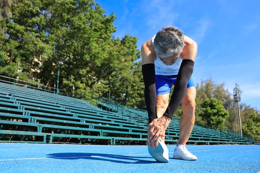 Senior Asian athlete doing stretching warm up for running in the professional blue track for professional exercise, sport training workout and healthy for longevity concept photo