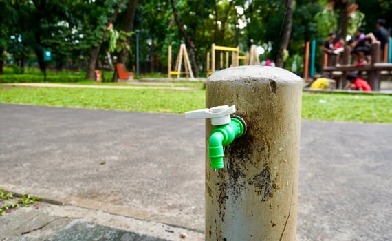 White and green plastic material tap water faucet isolated on horizontal ratio outdoor fresh eco green park and playground environment. photo