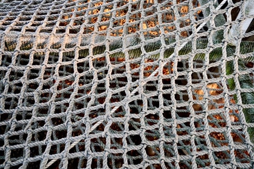 Thick rope with net pattern isolated on outdoor park playground horizontal ratio dry brown fallen leaves on ground background. photo