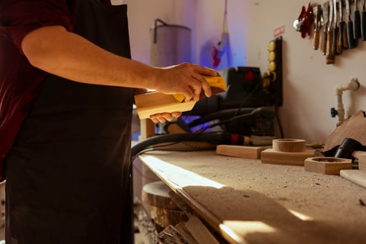 Woodworker in carpentry shop using sandpaper for sanding wooden surface before painting it, ensuring adequate finish. Woodworking specialist using abrasive sponge to fix damages suffered by wood photo