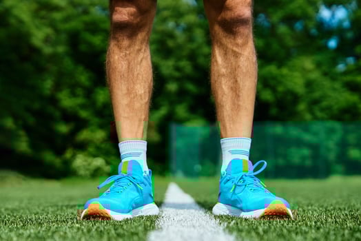 Athlete Wearing Bright Blue Running Shoes on Green Grass Track During Training photo