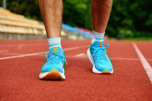 Athlete Wearing Bright Blue Running Shoes on Red Stadium Track During Training photo