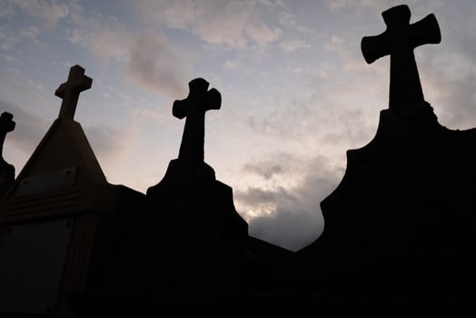 silhouette of grave crosses in a catholic cemetery at sunset photo