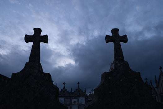 silhouette of grave crosses in a catholic cemetery at dusk photo