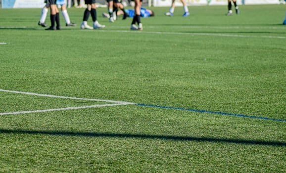 football field, in the background out of focus with a player lying on the ground between the legs of other players. photo