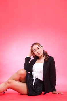 full portrait of young indonesia woman in career office sitting elegantly wearing black jacket, hands to the floor and hair back, for corporate, fashion, commercial, agency content photo
