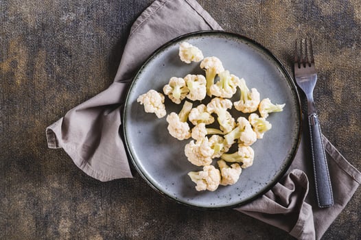 Close up of pieces of raw cauliflower for diet on a plate on the table top view photo